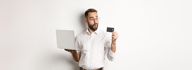 Zakupy Online Zdumiony Biznesmen Trzymający Laptopa Patrzący Pod Wrażeniem Karty Kredytowej Stojącej Nad Kimś