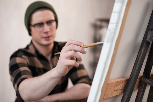 Zamazany mężczyzna artysta maluje na płótnie
