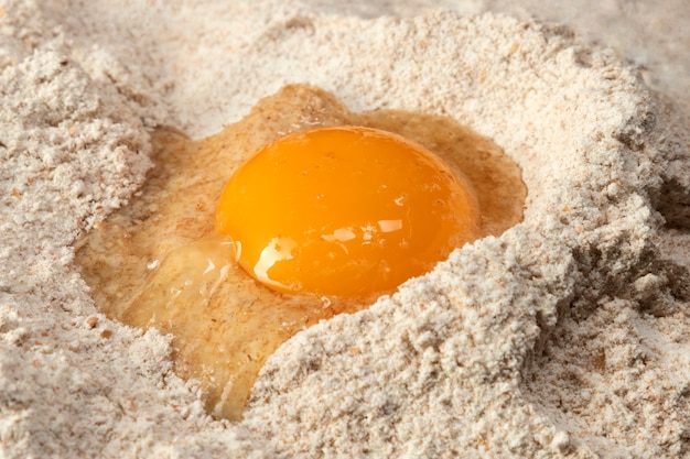 Zamknij na stosie mąki z surowym jajkiem