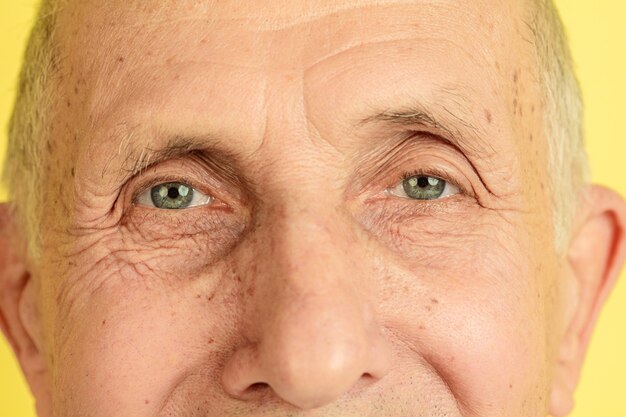 Zamknij oczy. Portret rasy kaukaskiej starszego mężczyzny na białym tle na żółtym tle studio. Piękny męski model emocjonalny. Pojęcie ludzkich emocji, wyrazu twarzy, sprzedaży, dobrego samopoczucia, reklamy. Copyspace.