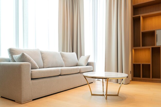 Zamknij się jasnobeżowa sofa z tkaniny z ciepłym, przytulnym porannym światłem z dużego okna w tle wnętrza domu