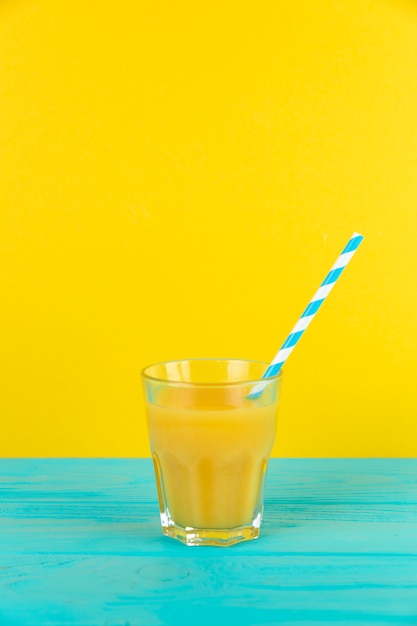 Bezpłatne zdjęcie zamknij się strzelać świeżego soku pomarańczowego szkła z żółtym tle