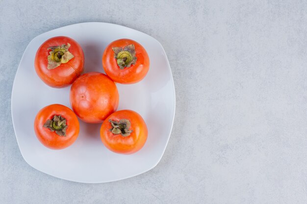 Zamknij się zdjęcie pomarańczowego persimmon na białym talerzu.