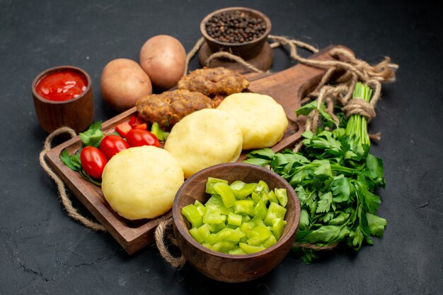 Zamknij widok na smaczne kotlety posiekane warzywa i keczup na kolację w ciemności