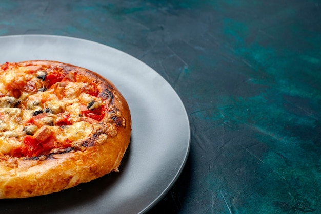 Zamknij widok z przodu mały ser pizza okrągły uformowany wewnątrz płyty na ciemnoniebieskim tle.