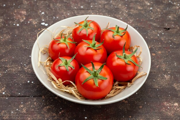 Zamknij widok z przodu świeże czerwone pomidory wewnątrz białej tablicy na drewnianym brązowym tle warzyw owocowy kolor