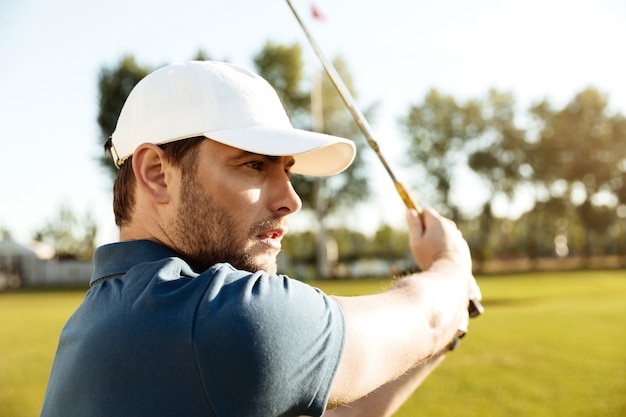 Zamyka up młody męski golfista uderza farwateru strzał