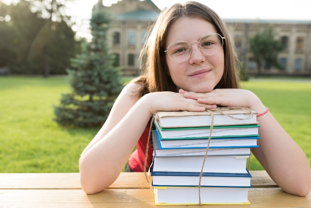 Zamyka w górę portreta highschool dziewczyny odpoczynkowa głowa na książkach