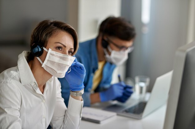 Zamyślony agent call center komunikujący się z klientem podczas pracy podczas epidemii koronawirusa