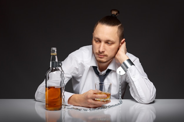 Bezpłatne zdjęcie zamyślony człowiek trzyma szklankę whisky