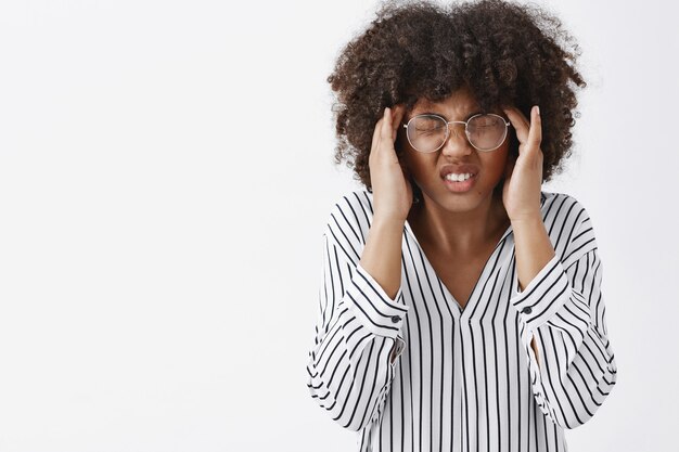 Zaniepokojona ciemnoskóra kobieta odczuwająca dyskomfort nie może skupić się na bólu głowy lub pamiętać ważnych informacji zamknięcie oczu zaciskanie zębów i trzymanie się za ręce na skroniach cierpienie z powodu bólu