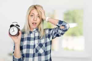 Bezpłatne zdjęcie zaniepokojona młoda kobieta, wskazując na zegar