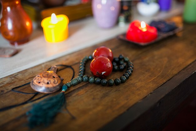 Zapalone świece z czerwonymi kulkami chińskimi; żółw i koraliki modlitewne na relaks na drewnianym biurku