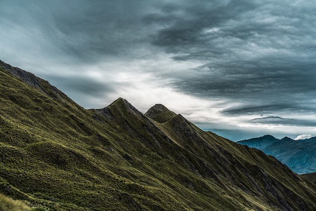 Zapierająca dech w piersiach sceneria historycznego szczytu Roys Peak dotykającego ponurego nieba w Nowej Zelandii