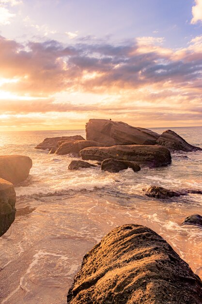 Zapierająca dech w piersiach sceneria kamienistej plaży o pięknym zachodzie słońca