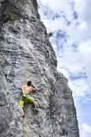 Bezpłatne zdjęcie zapierające dech w piersiach ujęcie młodego mężczyzny wspinającego się po wysokiej skale w champfromier we francji
