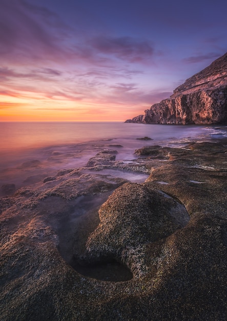 Bezpłatne zdjęcie zapierający dech w piersiach widok na morze i skały na malowniczym dramatycznym zachodzie słońca