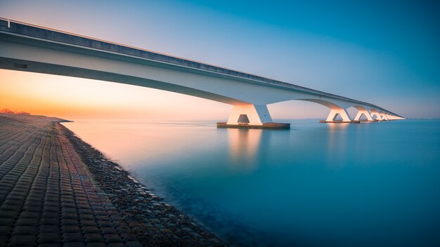 Zapierający dech w piersiach widok na most nad spokojną rzeką zrobiony w Zeelandbridge w Holandii