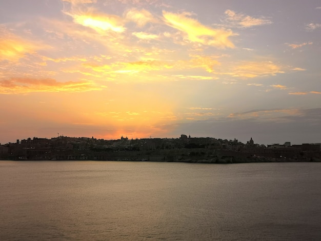 Zapierający dech w piersiach widok na zachód słońca na plaży otoczonej drzewami na Malcie