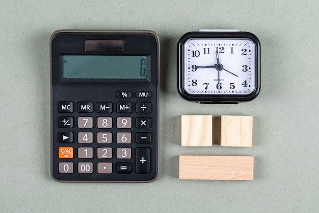 Zarządzanie czasem i księgowości pojęcie z magnifier, drewnianymi blokami, kalkulatorem i zegarkiem na szarego tła odgórnym widoku. obraz poziomy