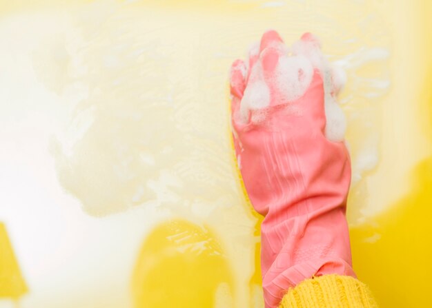 Zasięrzutny widok człowieka czyszczącego żółte tło gąbką