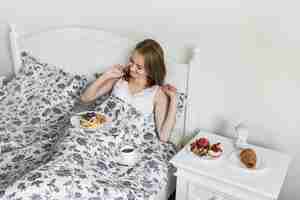 Bezpłatne zdjęcie zasięrzutny widok kobieta ma gofra śniadanie i kawę na łóżku