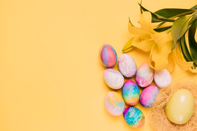 Zasięrzutny widok kolorowi Easter jajka z pięknym leluja kwiatem na żółtym tle