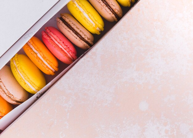 Zasięrzutny widok macaroons w białym pudełku nad textured tłem