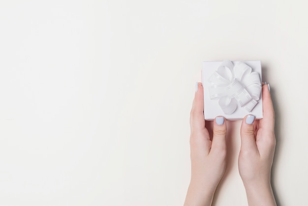 Zasięrzutny widok ręki trzyma białego prezenta pudełko odizolowywającego na białym tle