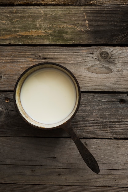 Zasięrzutny widok świeży mleko w starym rondlu nad drewnianym stołem