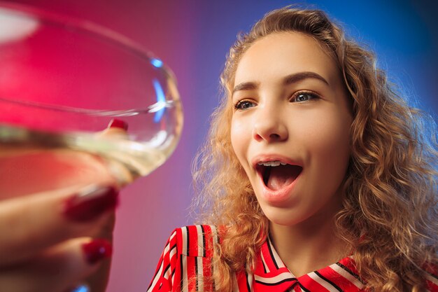 Zaskoczona młoda kobieta w strojach imprezowych pozuje przy lampce wina