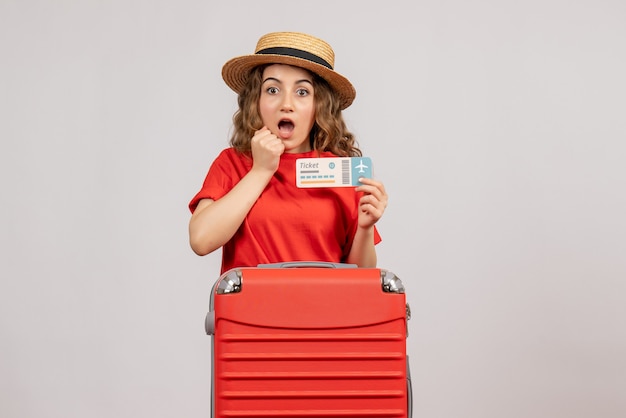 zaskoczona wakacyjna kobieta z czerwoną walizką trzymająca bilet