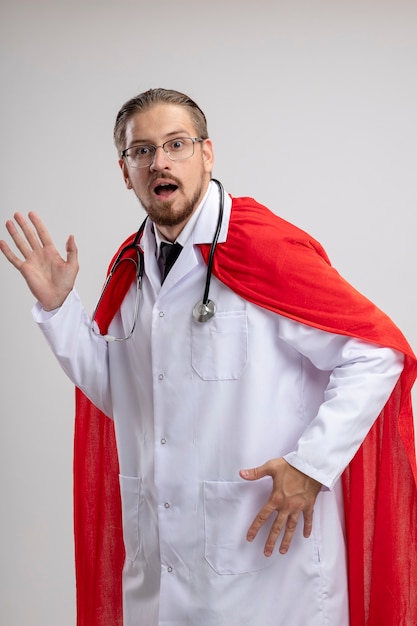 Zaskoczony, młody facet superbohatera na sobie szlafrok medyczny ze stetoskopem i okularami na białym tle