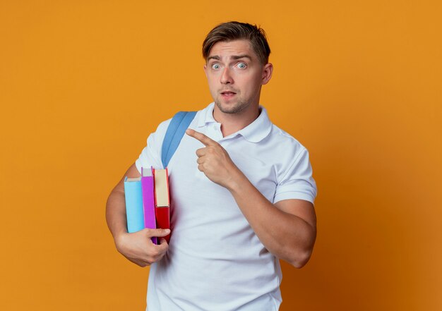 Zaskoczony młody przystojny student płci męskiej na sobie plecak trzymając książki