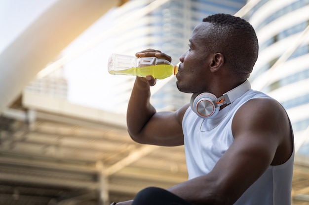 Zbliżeń zdrowie sporta mężczyzna woda pitna z butelki po biegać w mieście