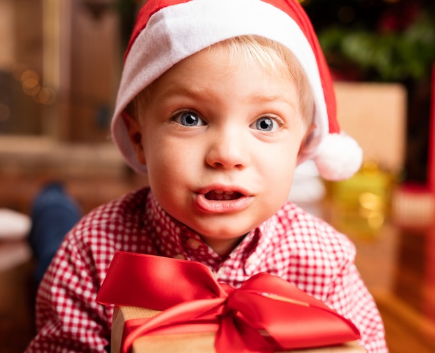 Zbliżenie adorable chłopiec z santa kapelusz i pudełko