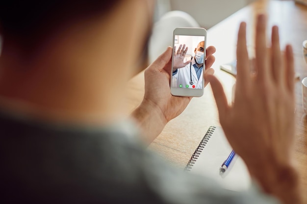 Zbliżenie afroamerykańskiego lekarza witającego swojego pacjenta podczas rozmowy wideo przez telefon komórkowy