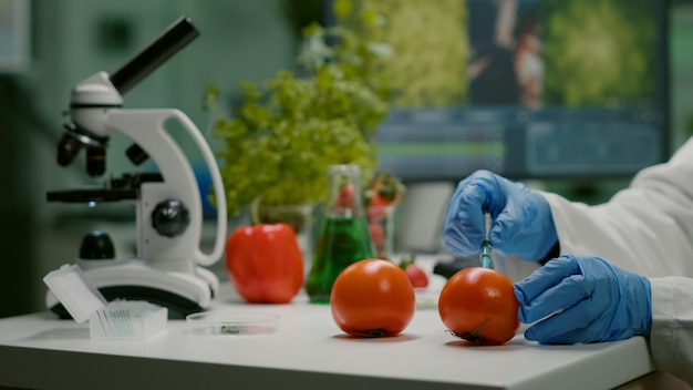 Bezpłatne zdjęcie zbliżenie chemika naukowca wstrzykującego organiczne pomidory z pestycydami do testu gmo