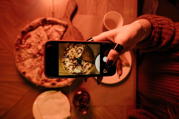 Zbliżenie dłoni biorąc zdjęcie pizzy
