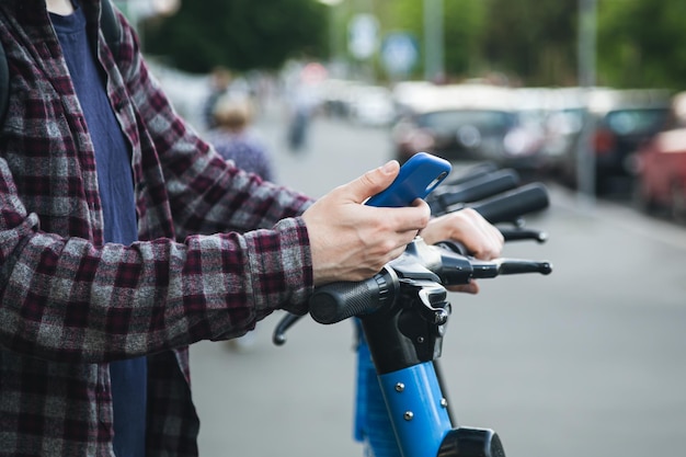 Zbliżenie dłoni człowieka za pomocą aplikacji mobilnej do wypożyczenia skutera elektrycznego