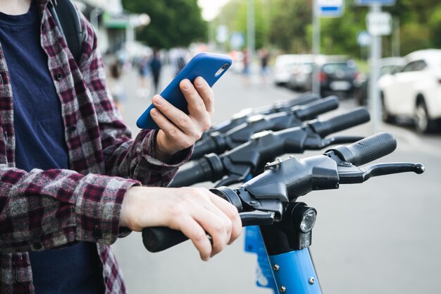 Bezpłatne zdjęcie zbliżenie dłoni człowieka za pomocą aplikacji mobilnej do wypożyczenia skutera elektrycznego