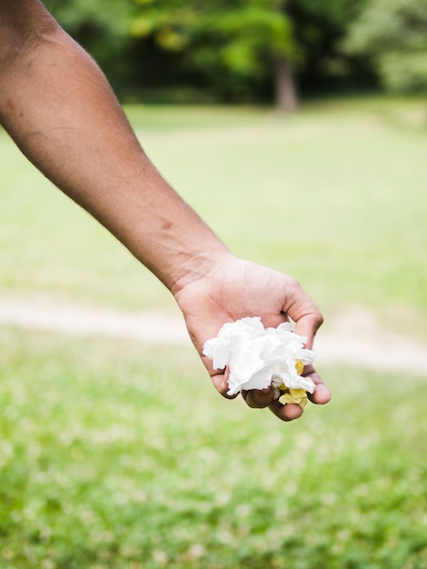Zbliżenie dłoni mężczyzny gospodarstwa zmięty papier w parku