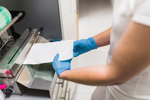 Zbliżenie dłoni pielęgniarki pracy na maszynach do pakowania woreczek uszczelniaczem