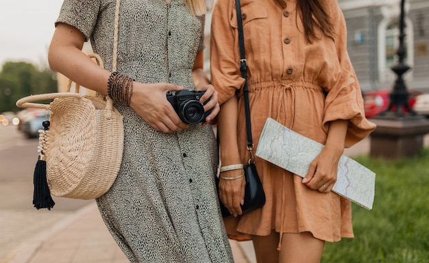 Zbliżenie dłoni szczegóły torba na akcesoria, mapa, aparat fotograficzny stylowych młodych kobiet podróżujących razem ubranych wiosną modny ubrany, styl uliczny