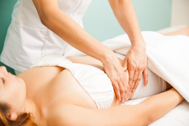 Zbliżenie dłoni terapeuty wykonującego masaż głębokich tkanek klientce w spa