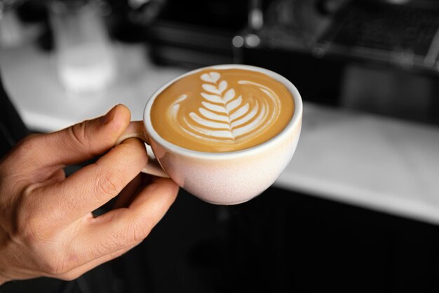 Zbliżenie dłoni trzymającej filiżankę kawy