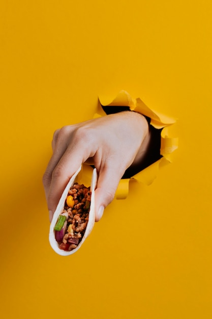 Bezpłatne zdjęcie zbliżenie dłoni trzymającej pyszne taco