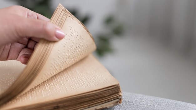 Zbliżenie dłoni trzymającej starą książkę Braille'a