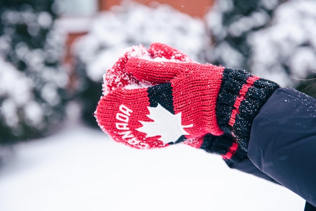 Zbliżenie dłoni w czerwonych kanadyjskich rękawiczkach tworzy śnieżkę ze śniegu