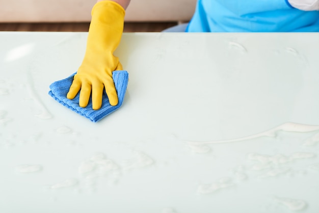 Zbliżenie dłoni w tabeli czyszczenia rękawic z piankowym detergentem